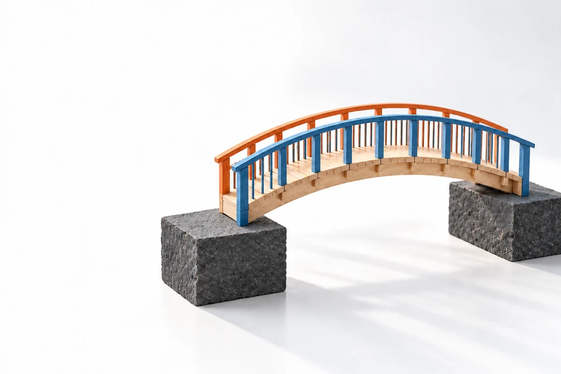 A maple footbridge with blue and orange railings connects two dark stone supports.